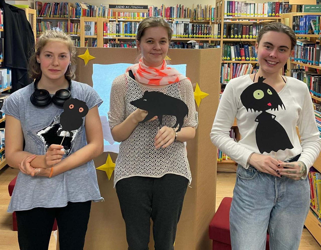 Drei Mädchen der Aiserkids mit Schattenfiguren haltend vor dem Schattentheater