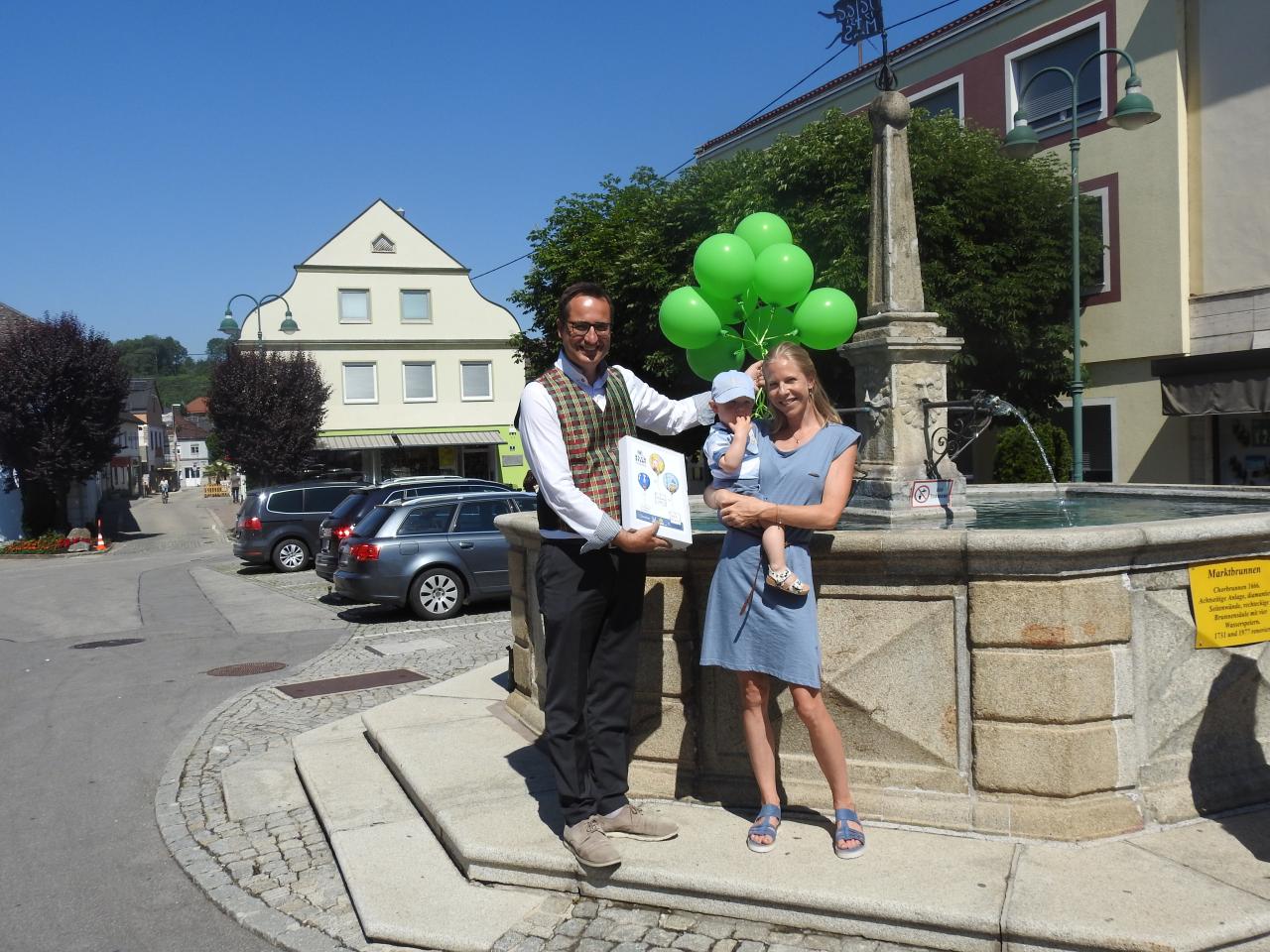 Bürgermeister mit Luftballons und einer Mama mit Kind