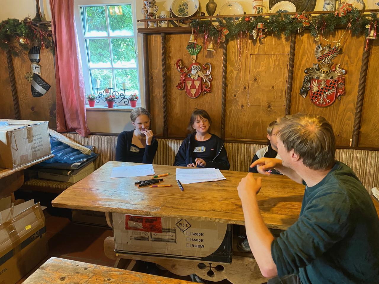 Kinder und ein Betreuer in sitzen an einem Tisch