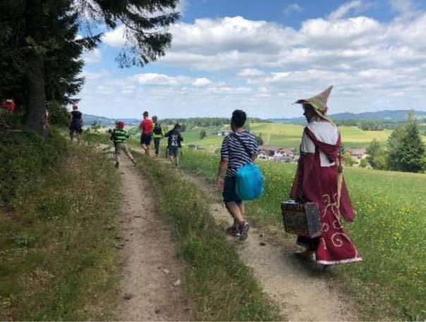 Menschen wandern mit der Märchenerzählerin auf einem Weg entlang