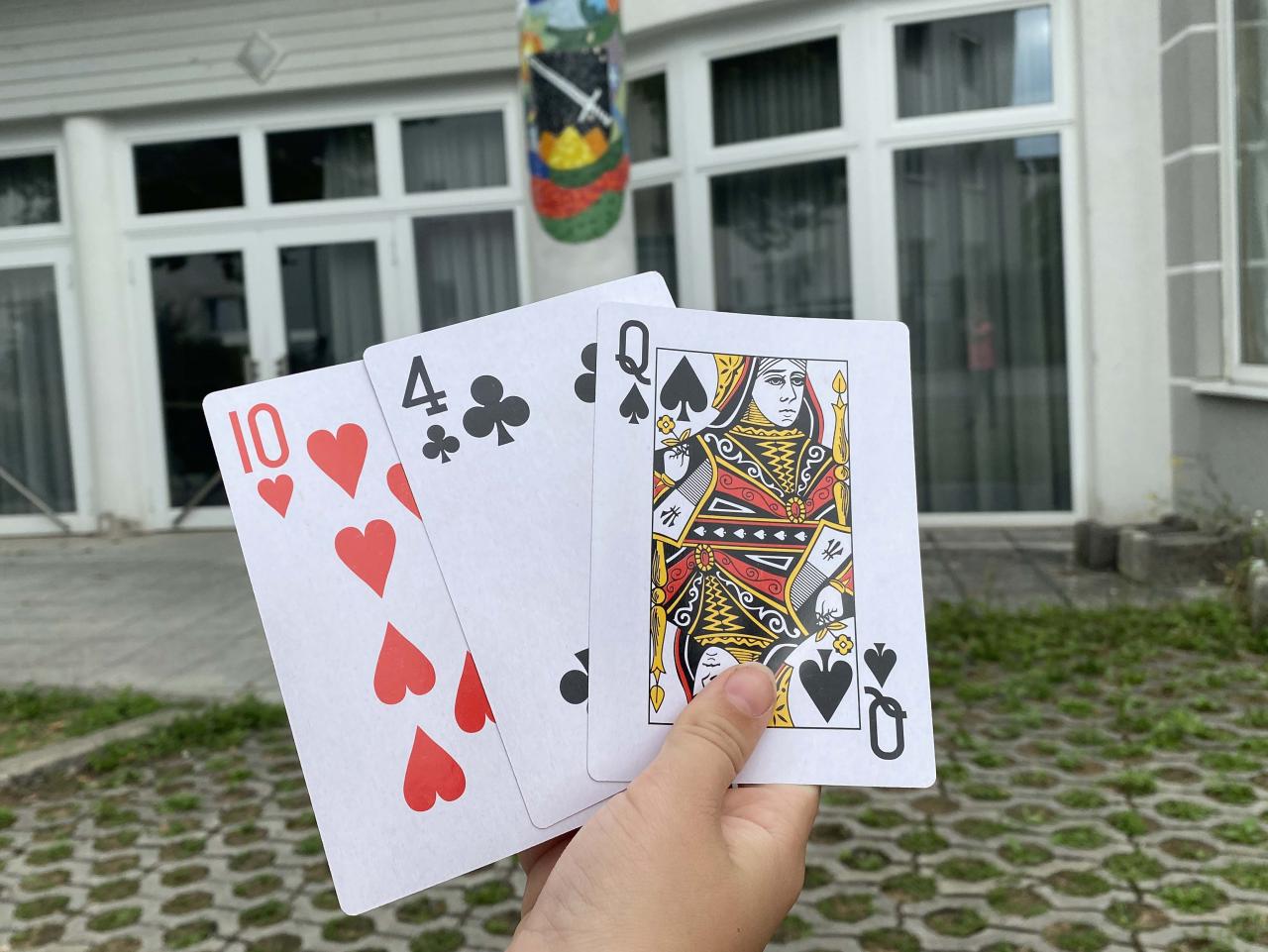 Hand hält Spielkarten vor dem Volksheim Schwertberg