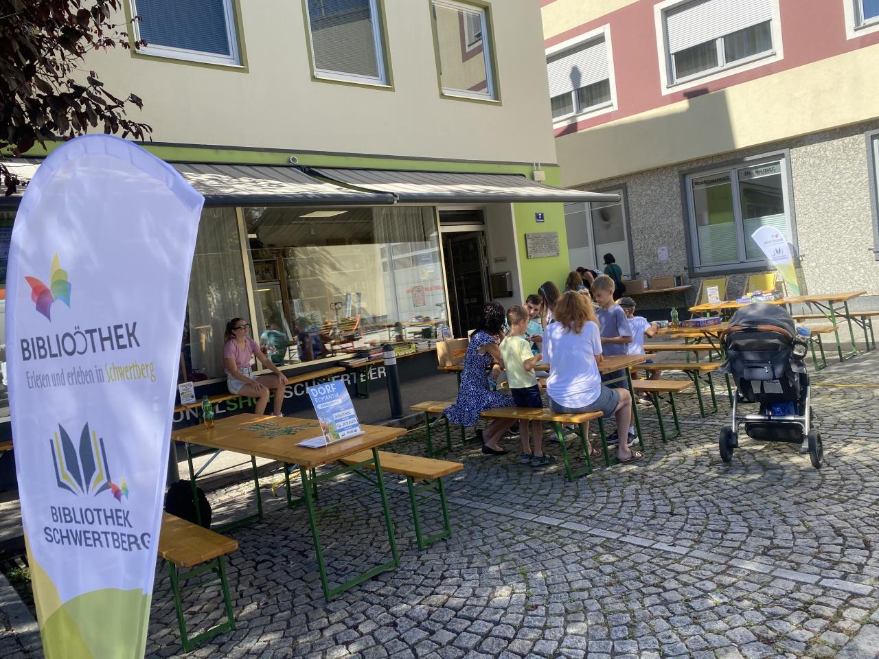 Menschen sitzen vor der Bibliothek auf Bänken