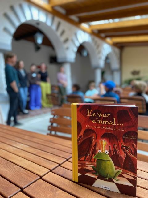 Ein Märchenbuch, dahinter eine Menschengruppe