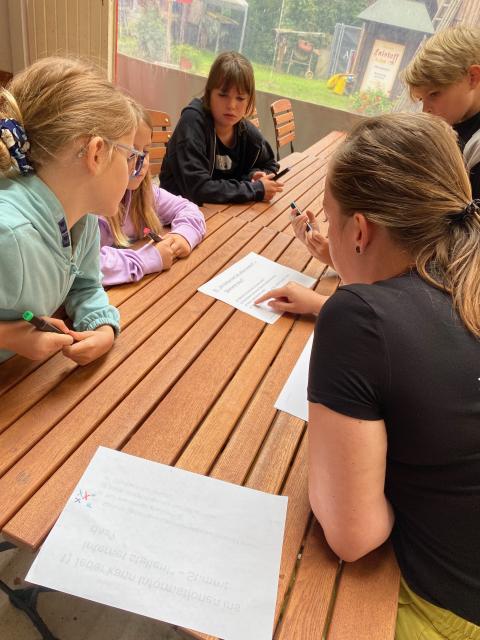 Eine Gruppe Kinder sitzen am Tisch und studieren einen Zettel