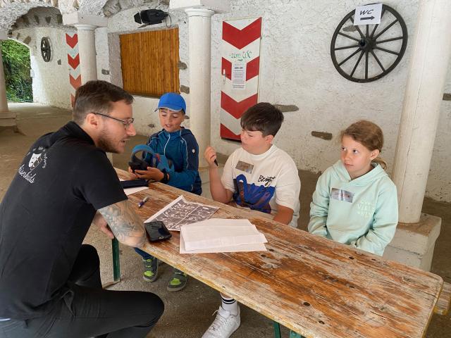 Kinder und ein Erwachsener sitzen an einem Tisch