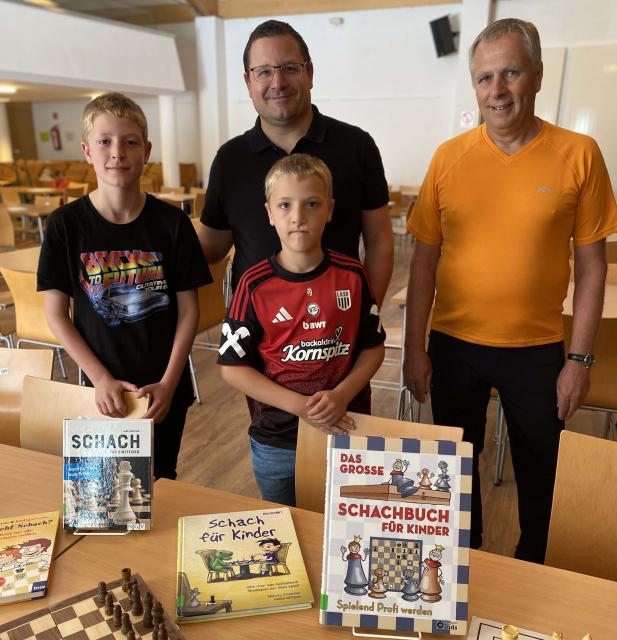 vier Personen stehen vor Tisch mit Schachbrettern