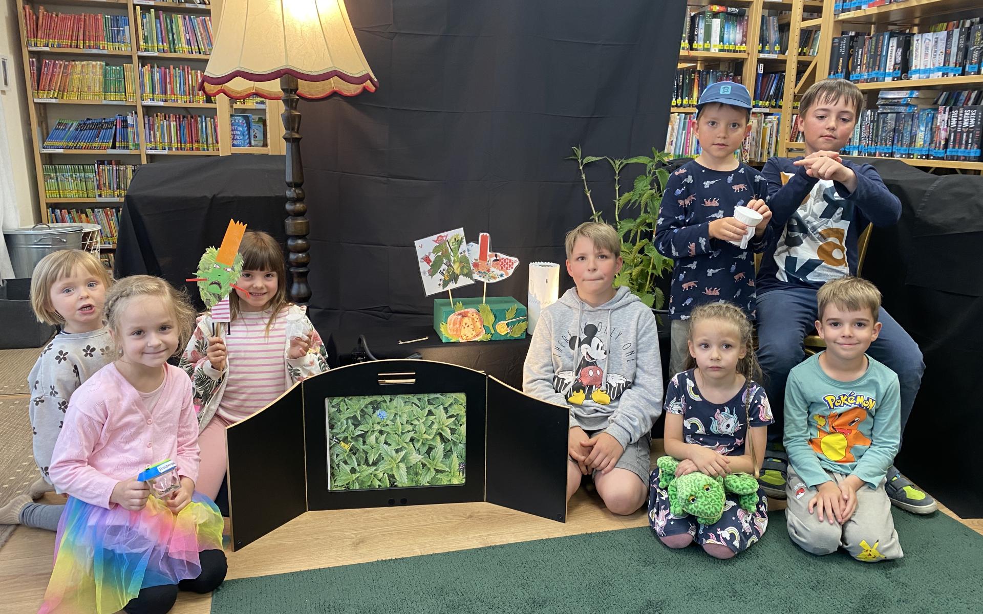 einige Kinder sitzen am Boden neben Brennnesseln