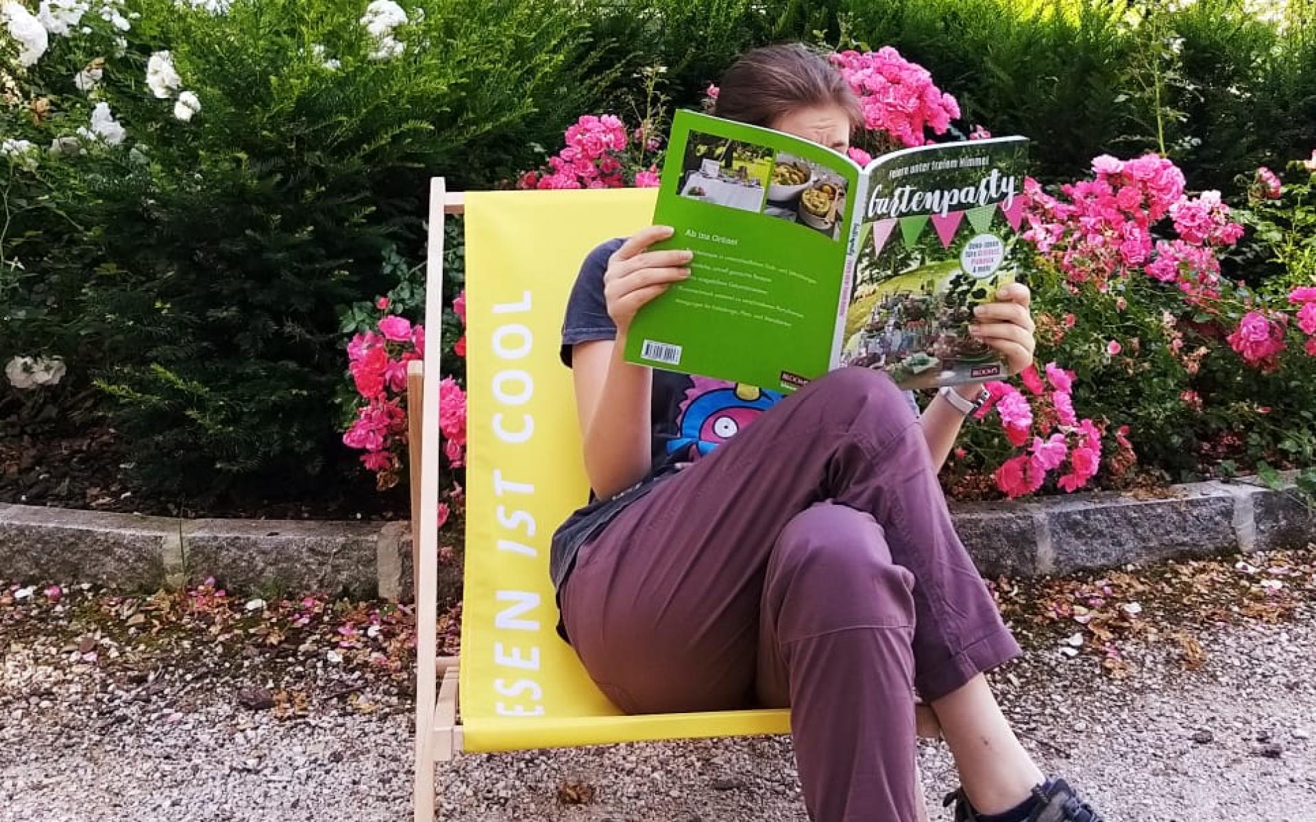 Eine Frau am Liegestuhl mit einem Buch in der Hand