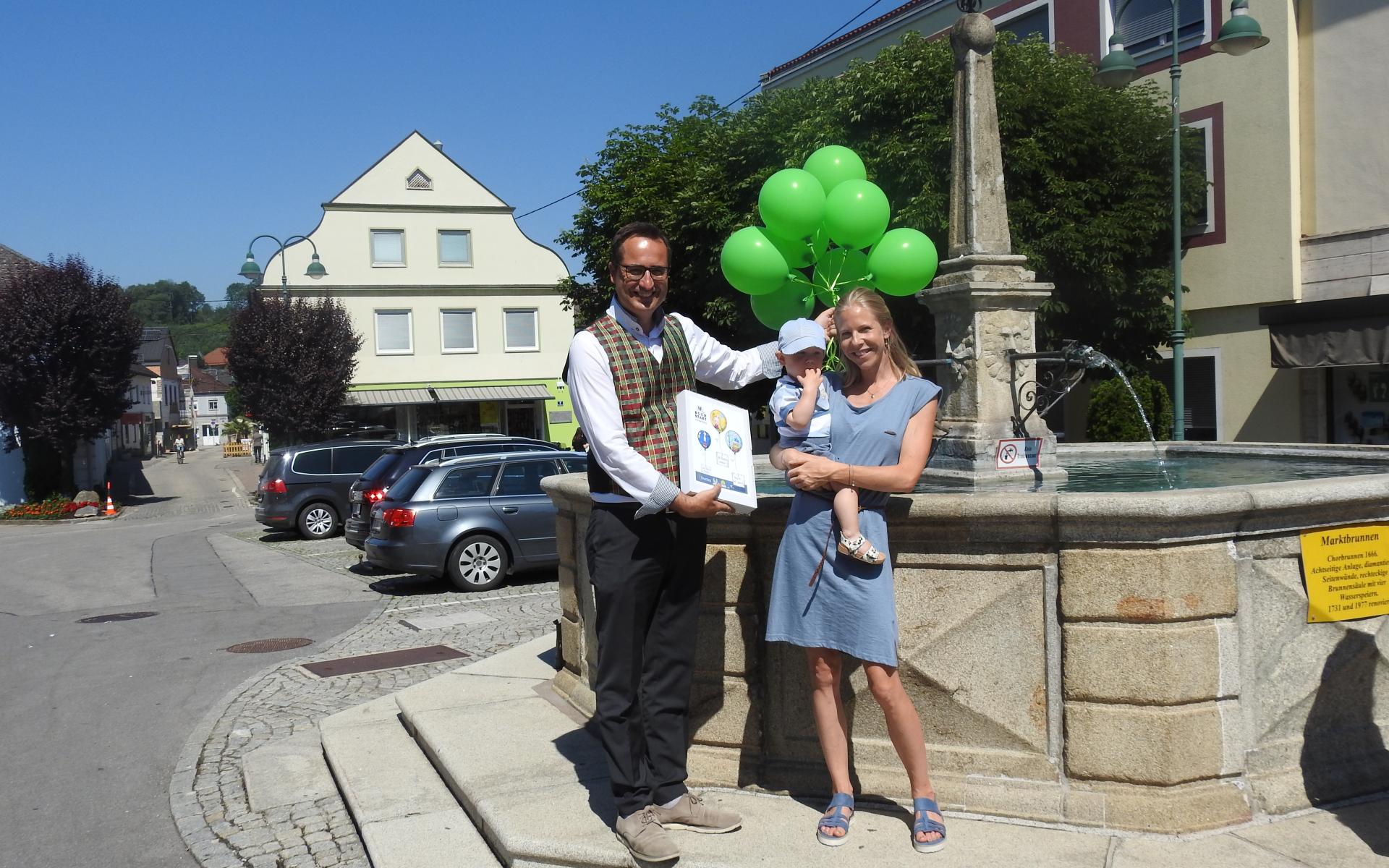 Bürgermeister mit Luftballons und einer Mama mit Kind