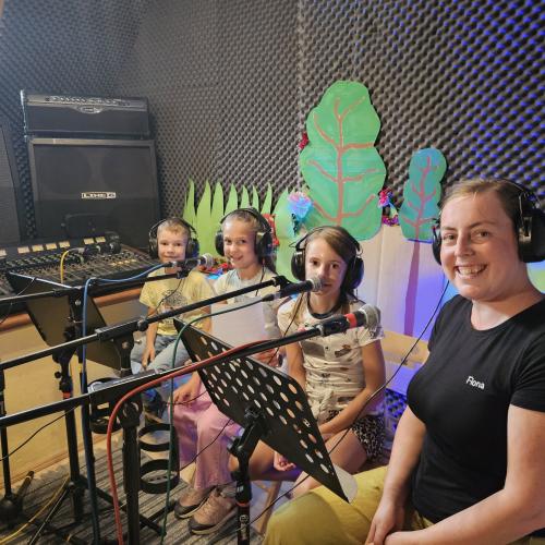 Drei Kinder und eine Frau im Tonstudio mit Kopfhörer