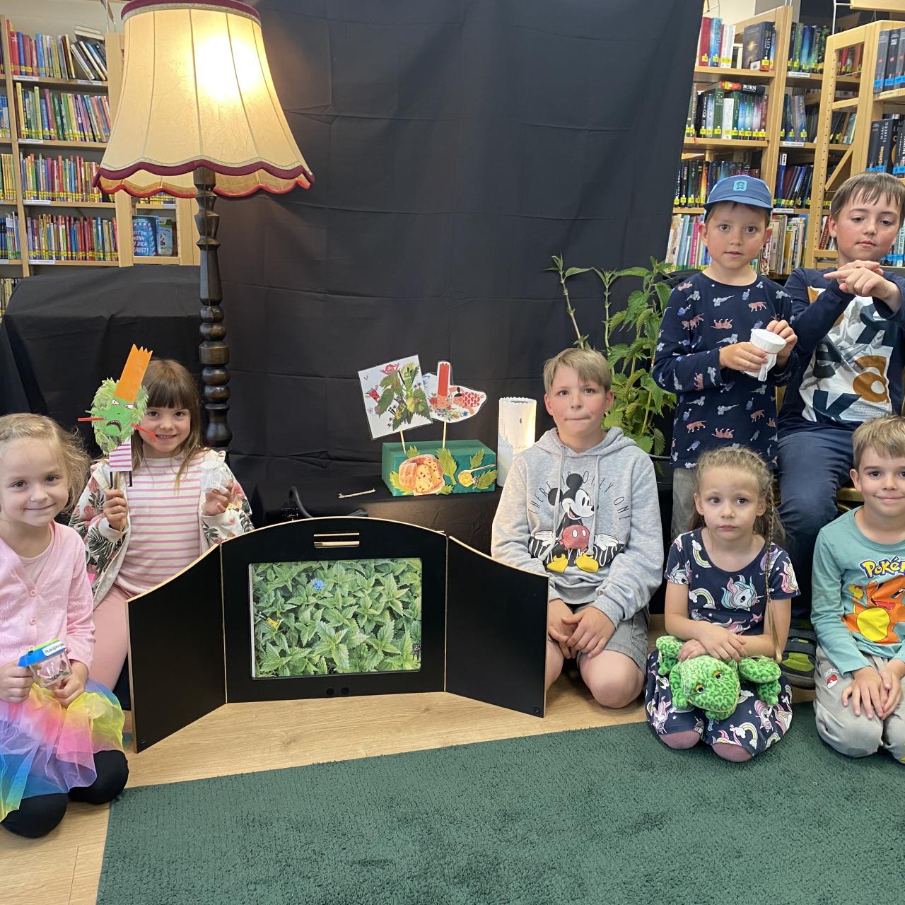 einige Kinder sitzen am Boden neben Brennnesseln