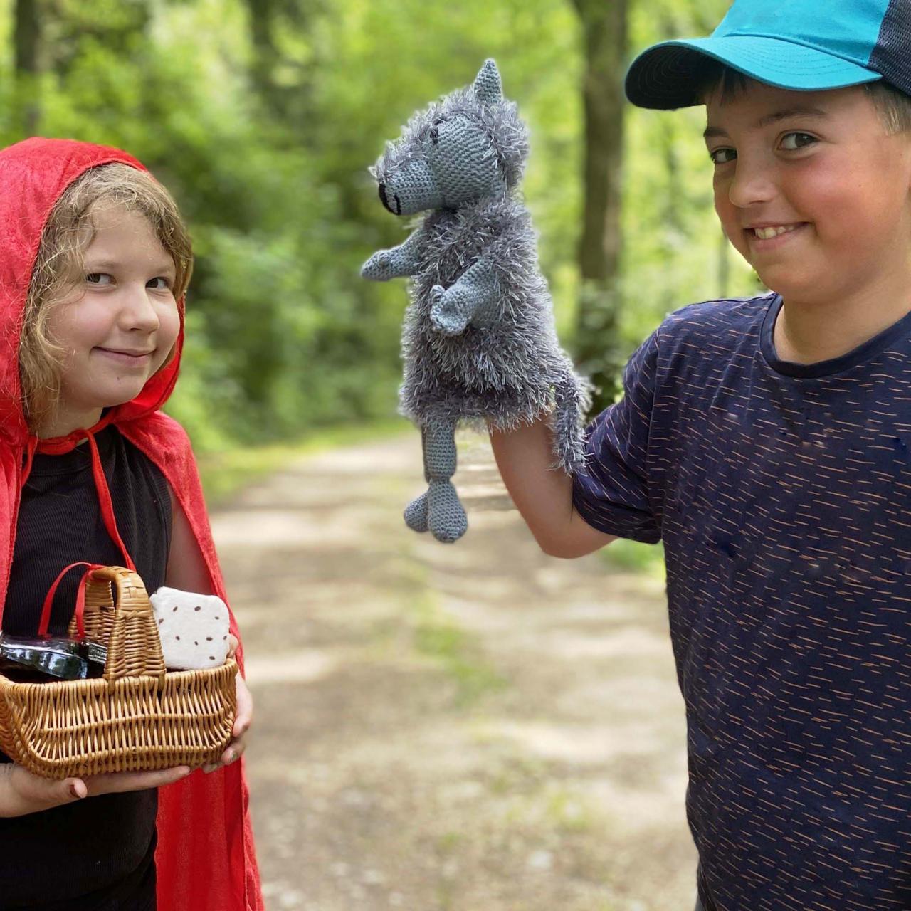 Ein Mädchen mit Rokäppchenumhang und eine Junge mit einer Wolfshandpuppe