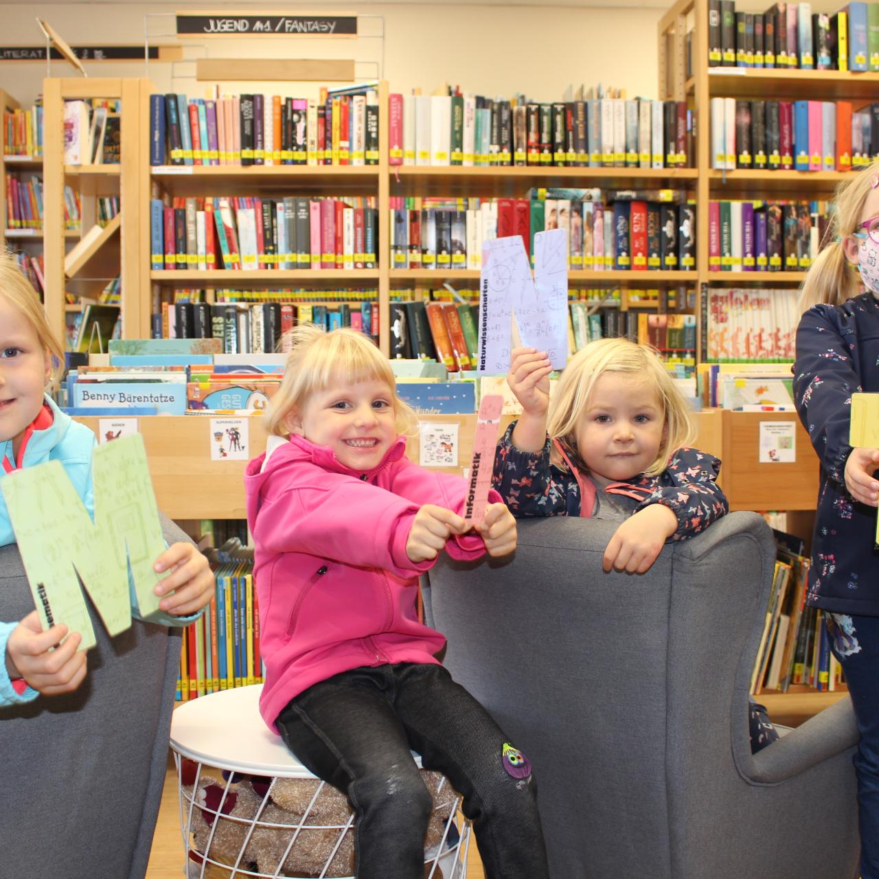 Vier Kinder halten die Buchstaben MINT in der Hand