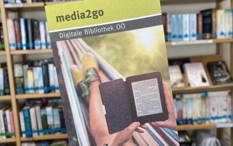 Ein Folder von Media2go vor einem Regal mit Büchern