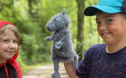 Ein Mädchen mit Rokäppchenumhang und eine Junge mit einer Wolfshandpuppe