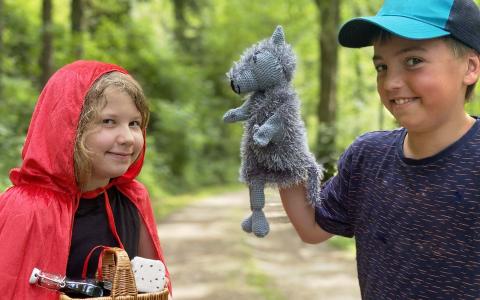 Ein Mädchen mit Rokäppchenumhang und eine Junge mit einer Wolfshandpuppe