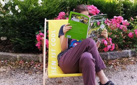 Eine Frau am Liegestuhl mit einem Buch in der Hand