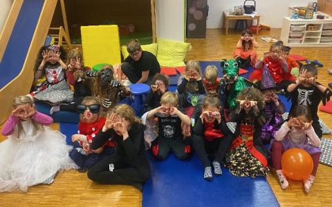 Viele Kinder sitzen am Boden und sind gruselig verkleidet
